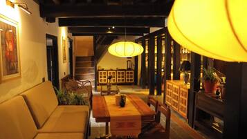 Un comedor con una mesa de madera, sillas, un sofá y una escalera al fondo.
