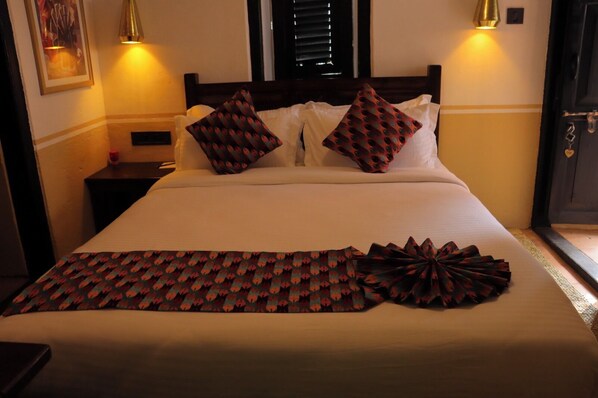 Un lit avec des coussins à motifs, un plaid décoratif et des lampes de chevet.
