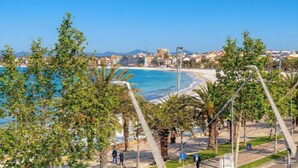 A coastal cityscape with a beach, palm trees, and buildings in the background. - Sunset Harbor Penthouse with a sun-drenched panoramic terrace and garage (Alghero)