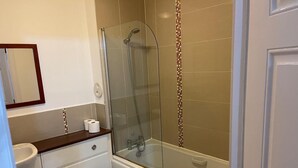 Een badkamer met een douchecabine van glas, een toilet en een wastafel.