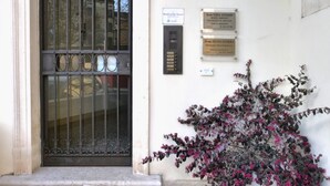 A building entrance with a metal gate, plaques on the wall, and a flowering plant. - La Finestra sul Fiume - 5 min from the Basilica (Vicenza)
