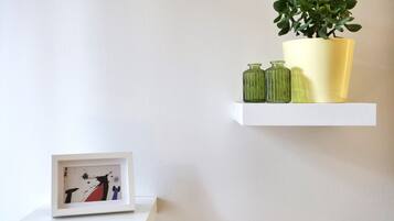 Zwei weiße, schwebende Regale an einer schlichten Wand, jedes mit unterschiedlichen Gegenständen.