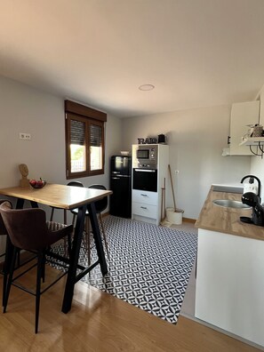 A compact kitchen with a dining table, chairs, a microwave, and a coffee machine. - 5 LOFT with spectacular terrace (Salamanca)