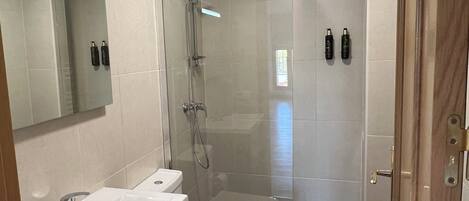 A bathroom with a shower, toilet, and sink.