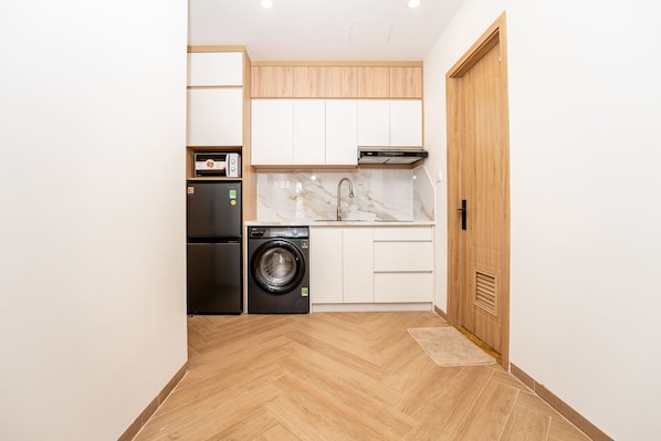 A compact kitchen with a washing machine, a built-in oven, and a sink. - Harmony Phu Quoc (Phu Quoc)
