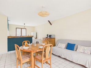 A dining area with a wooden table, chairs, and a kitchen area with a microwave. - 450m from the Arès Pier, house for 4 (Arès)
