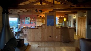 A rustic interior with a wooden bar, a large chimney, and a view through the open space. - Starboard Sunset – Coastal Views, Hot Tub & Private Retreat (Bodega Bay)