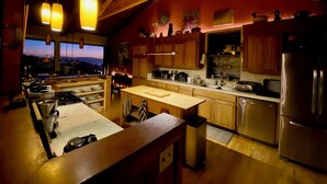 A modern kitchen with wooden cabinets, stainless steel appliances, and pendant lighting. - Starboard Sunset – Coastal Views, Hot Tub & Private Retreat (Bodega Bay)