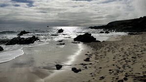 Une plage avec des affleurements rocheux, une étendue de sable et l’océan.