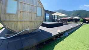 Une structure en forme de tonneau, faite de bois, dotée d’une terrasse, d’un espace salon extérieur et d’un espace piscine.
