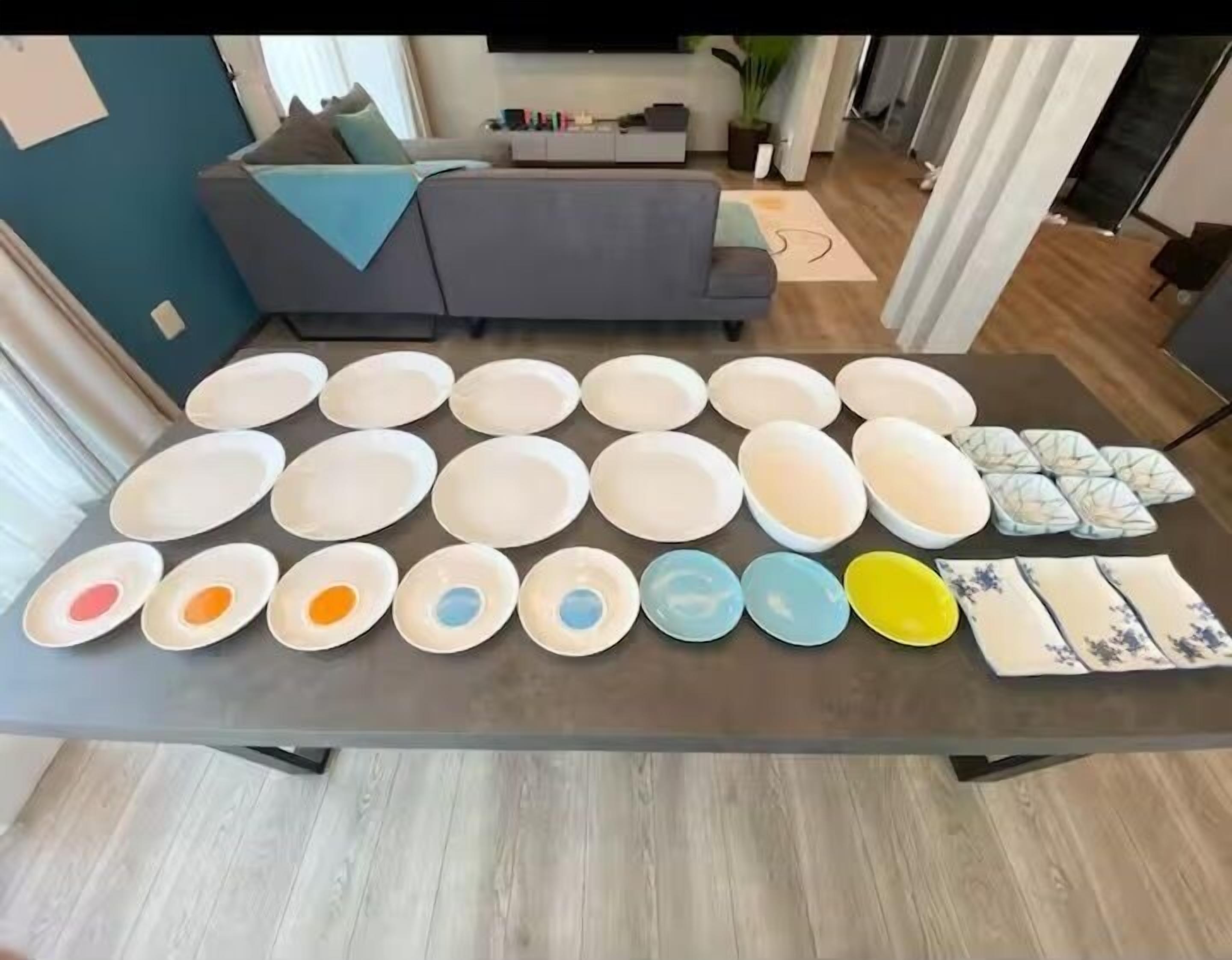 A dining table with various plates and bowls, a sofa, and a plant in a living area.