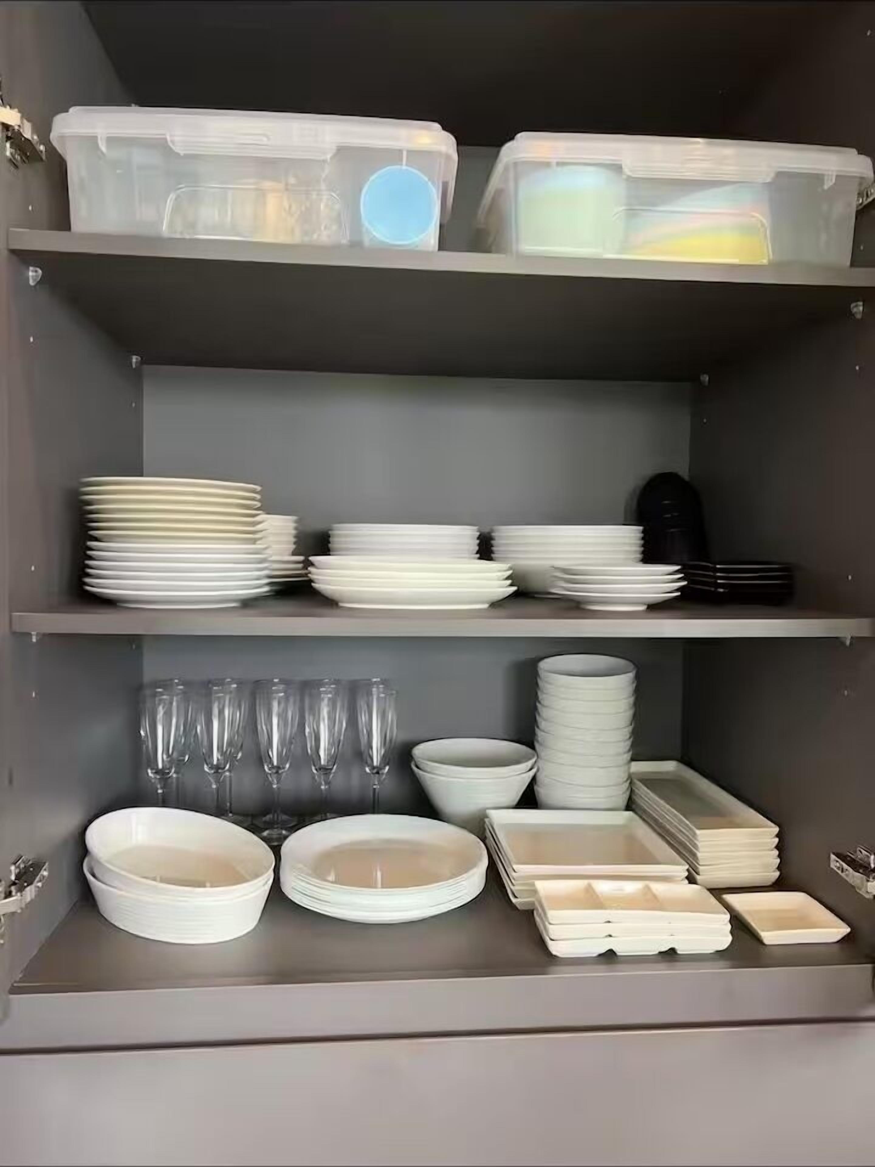 A storage unit with shelves holding plates, bowls, glasses, and containers.