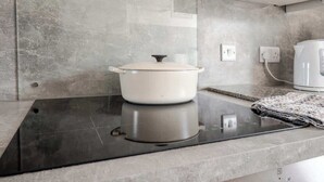 Une cuisine avec une cuisinière, une casserole et une bouilloire posés sur le plan de travail.