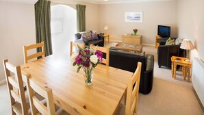A furnished living room with a dining table, sofa, and TV. - Simmental Cottage Daviot (Inverness)