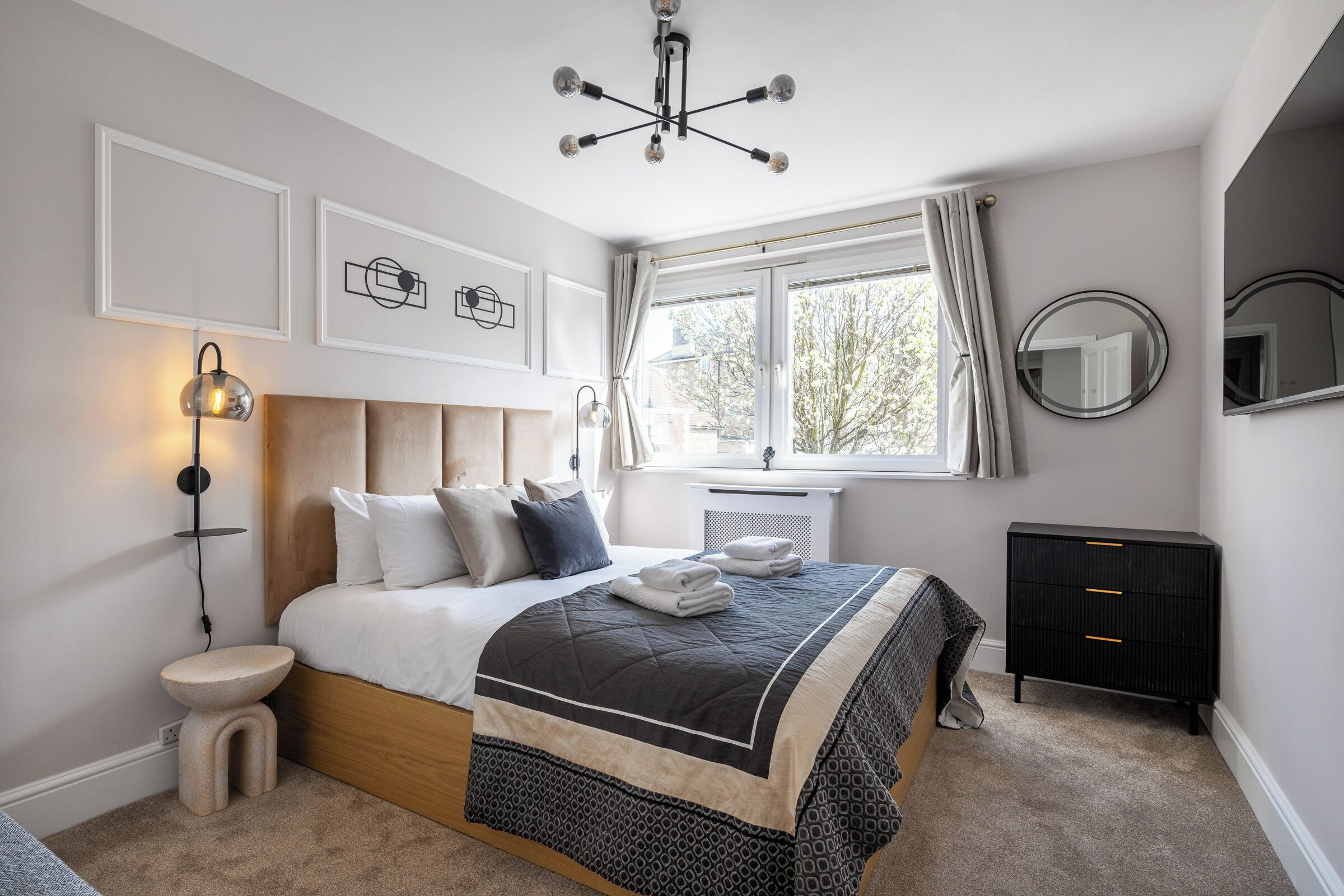 Un dormitorio con cama, mesita de noche, lámpara, cómoda y ventana con cortinas.