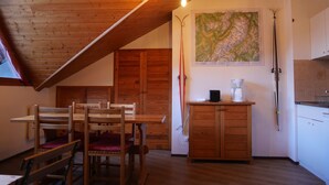 Ein Holzinterieur mit einem Esstisch, Stühlen, einer Karte an der Wand, einer Kaffeemaschine und einem Ski.