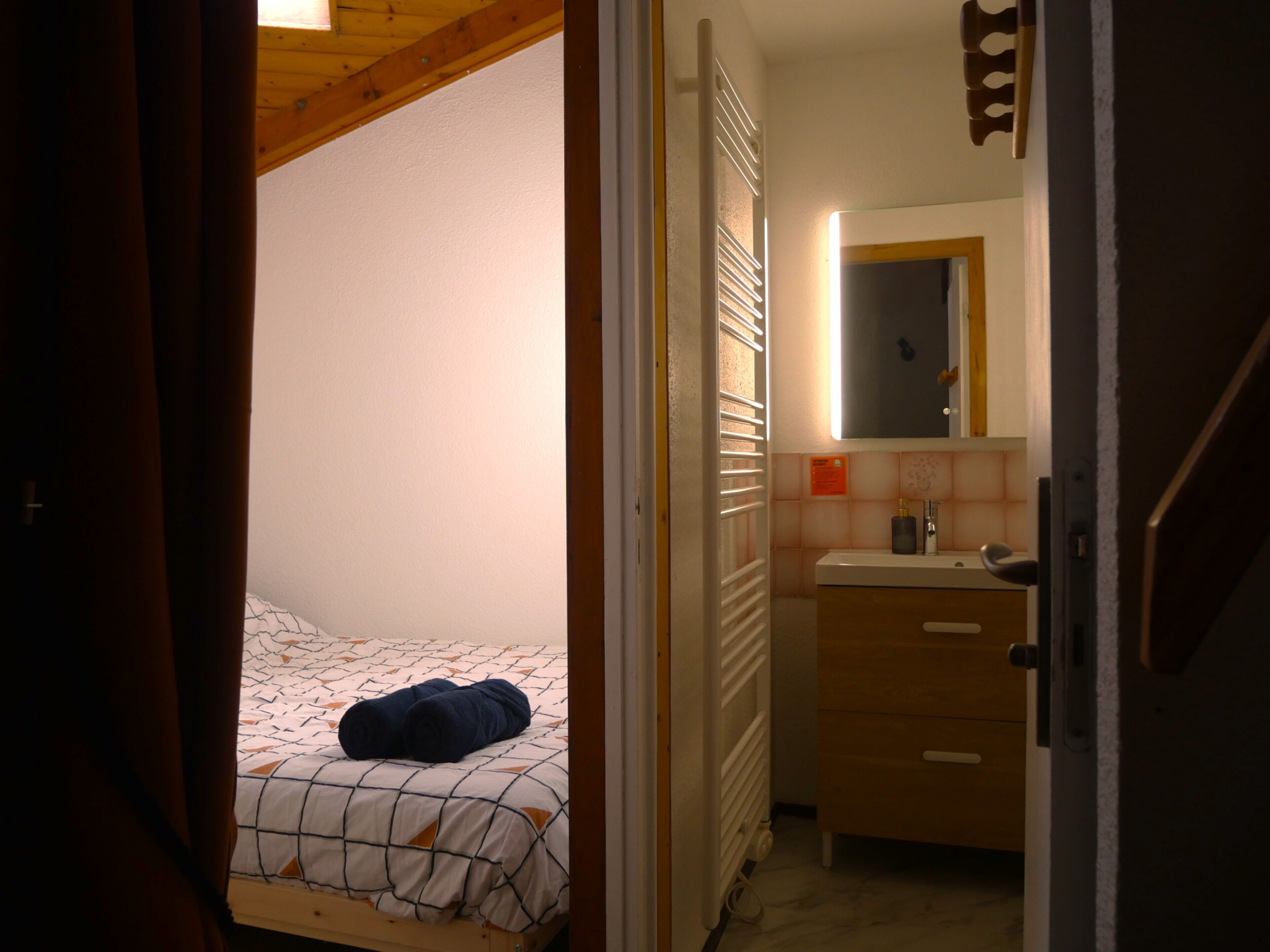 A bedroom with a bed, a bedside table, a mirror, and a radiator.