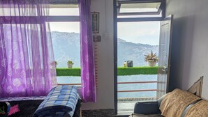 A room with two beds, a view of a mountainous landscape, and a balcony with potted plants. - LuxeHaven Homestay-a Peaceful Escape (Darjeeling)
