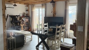 A spacious living area with a dining table, chairs, a sofa, and a bookshelf. - Belle Vue Bed and Breakfast: Recharge Your Batteries in the Countryside. (Fraisses)
