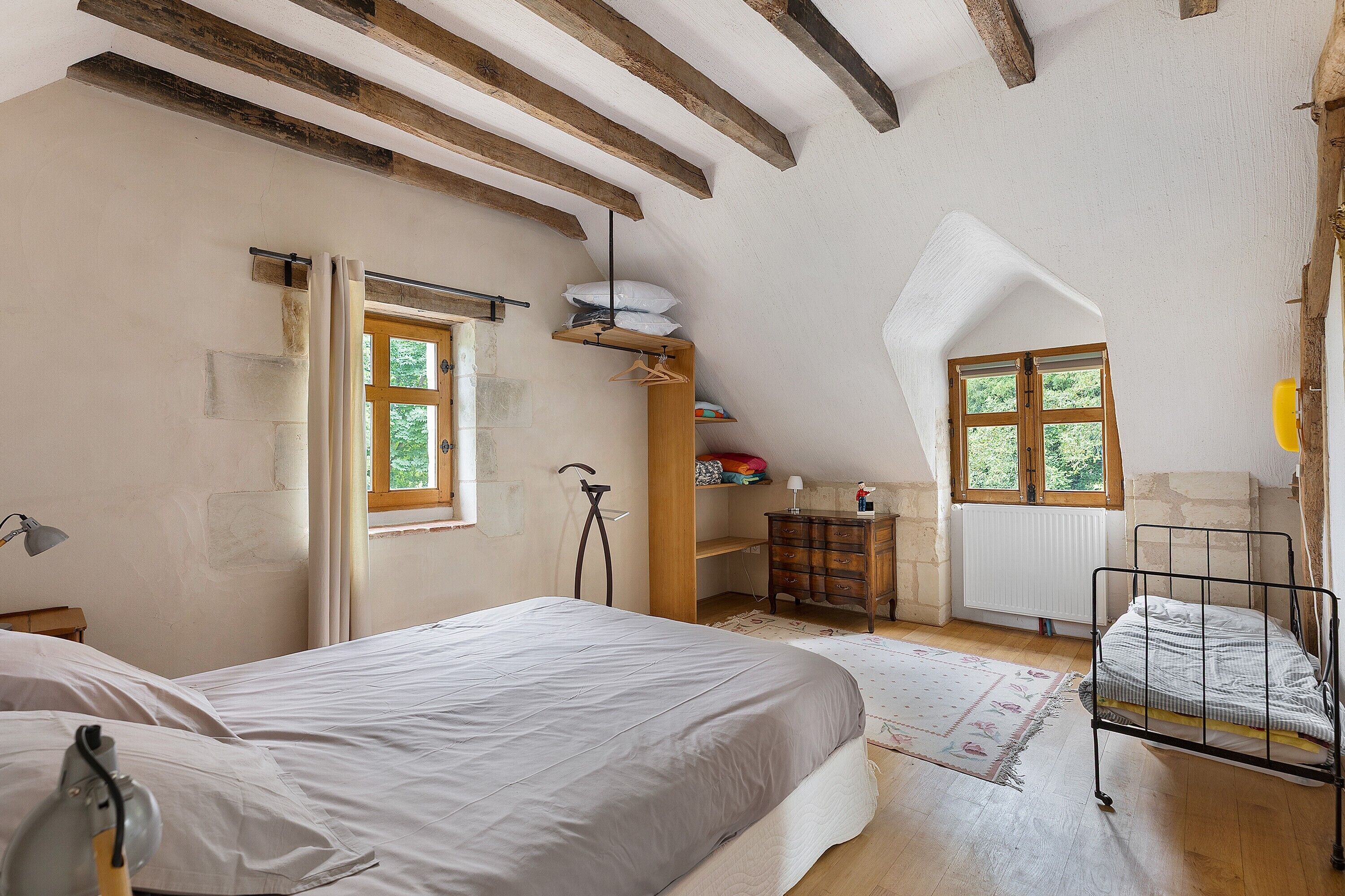 Ein Schlafzimmer mit einem Bett, einem Schminktisch, einem Heizkörper und einem Fenster.