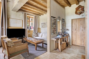 A cozy living room with a sofa, a coffee table, a TV, and a wooden desk with a mirror and various items. - La Motte Wilhelm de Sonnay – Relais du Château de Sonnay (Cravant-les-Côteaux)