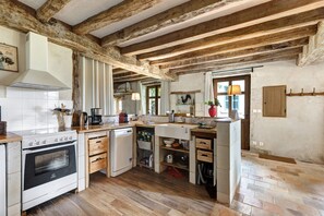 Une cuisine rustique avec des poutres apparentes, un poêle blanc et un lave-vaisselle.