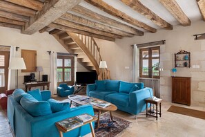 Ein Wohnzimmer mit Treppe, blauen Sofas, einem Couchtisch und einem Holzkabinett.