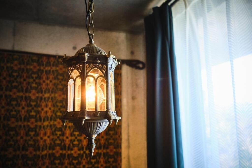 A hanging lantern with intricate designs, a patterned wall, and a window with curtains.