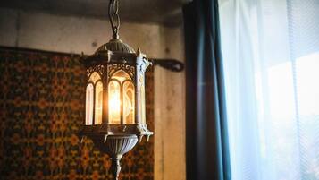 A hanging lantern with intricate designs, a patterned wall, and a window with curtains.
