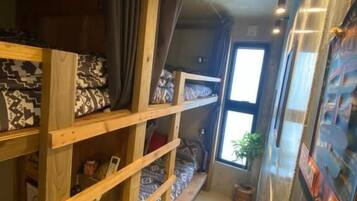 Een kleine kamer met stapelbedden, een raam en een muur met een surfmotief.