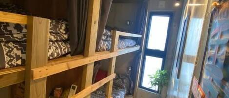 Una habitación pequeña con literas, una ventana y decoración temática de surf.