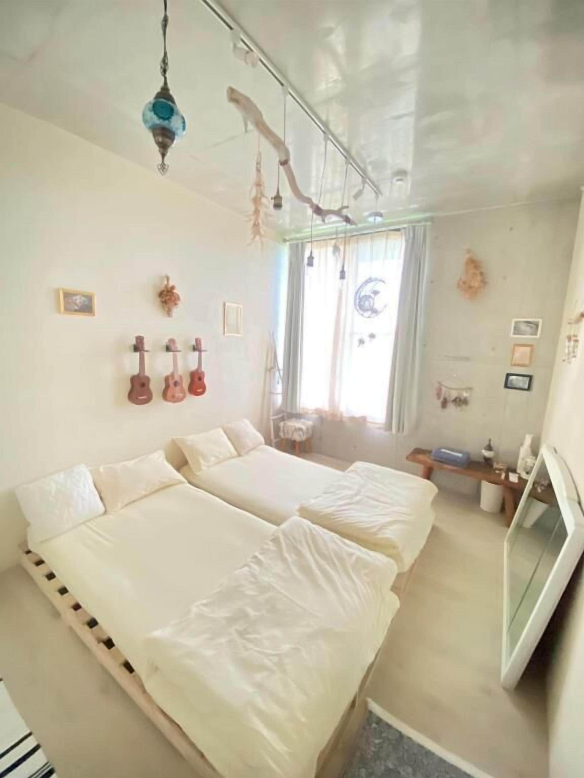 A bedroom with two beds, a TV, and a window with curtains.