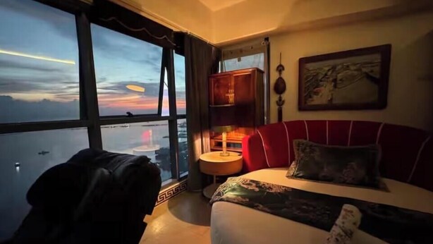 A hotel room with a large window, a bed, a nightstand, and a chair. - 康宿·夕观居｜日落海景双卧套房
KanStay Sunset View | 2BR Sunset Ocean View Suite (Manila)