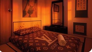 A bedroom with a bed featuring a Louis Vuitton pattern, a mirror, and artwork on the walls. - 康宿·夕观居｜日落海景双卧套房
KanStay Sunset View | 2BR Sunset Ocean View Suite (Manila)