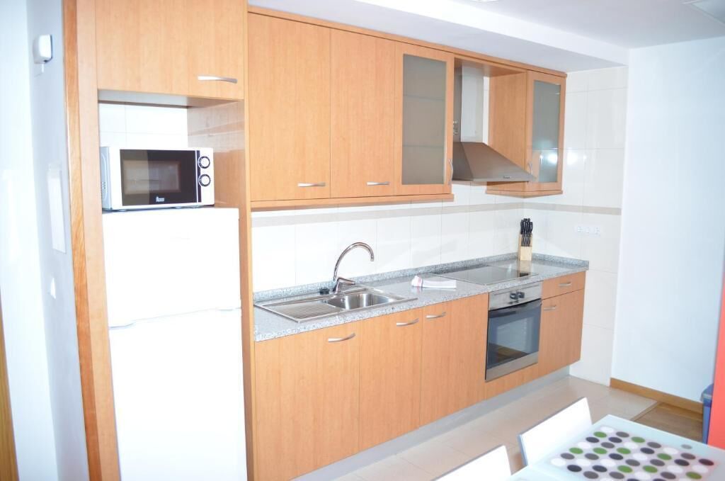 A compact kitchen with wooden cabinets, a microwave, a sink, and a stove.