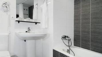 A bathroom with a white sink, a mirror, a toilet, and a shower area.
