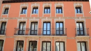 A multi-story building with a consistent architectural style, featuring balconies with wrought iron railings and large windows. - Apartamentos Los Sitios (Zaragoza)