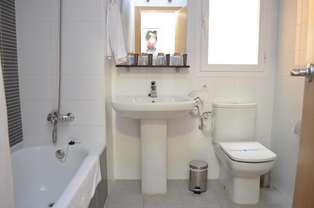 Un baño con bañera, lavamanos pedestal, inodoro y ventana.