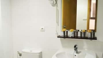 Ein Badezimmer mit Toilette, Waschbecken, Spiegel und einem kleinen Mülleimer.