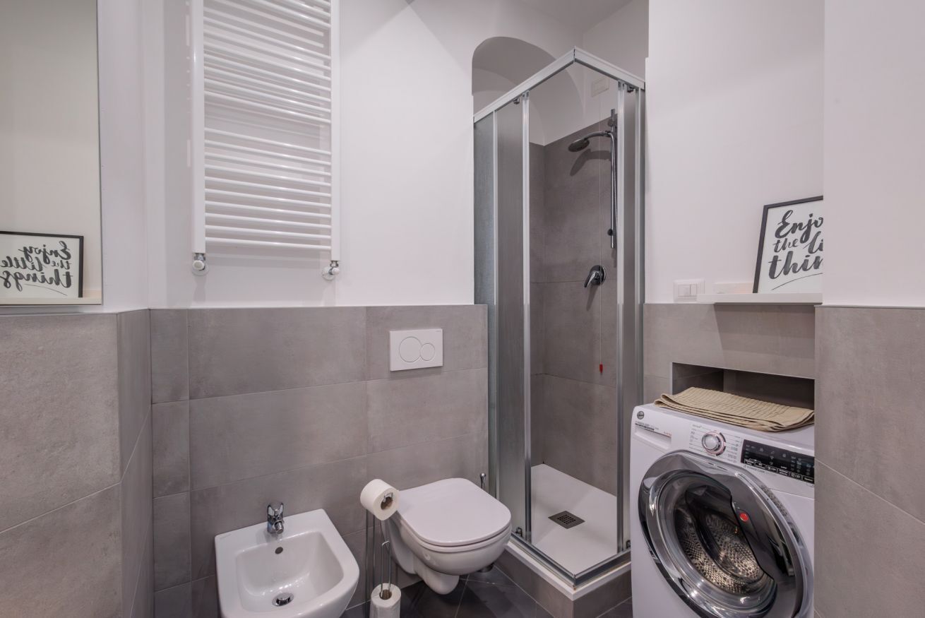 Ein Badezimmer mit Dusche, Toilette, Bidet und Waschmaschine.
