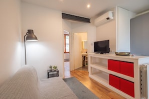 A modern living room with a sofa, a lamp, a TV, and a kitchen area with red cabinets. - GuestHost - Comfortable 50m2 apartment, ideal for 4 people, located on the second floor of a renovated period building without lift.The accommodation is located in the center of Città Bassa, the modern and commercial heart of Bergamo, a short distance f (Bergamo)