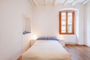 A bedroom with a bed, bedside tables, a window, and a radiator. - GuestHost - Comfortable 50m2 apartment, ideal for 4 people, located on the second floor of a renovated period building without lift.The accommodation is located in the center of Città Bassa, the modern and commercial heart of Bergamo, a short distance f (Bergamo)