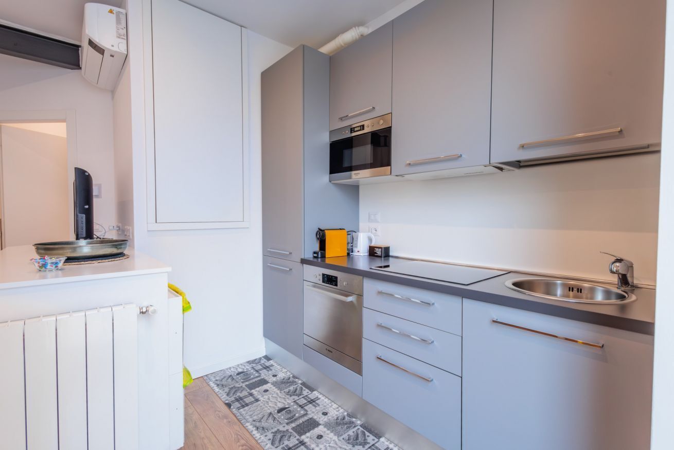 Eine moderne Küche mit weißen Schränken, Edelstahlgeräten und einem eingebauten Backofen.