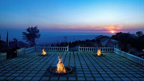 A terrace with a fire pit and a view of the sunset. - Rakkh Resort (Palampur)
