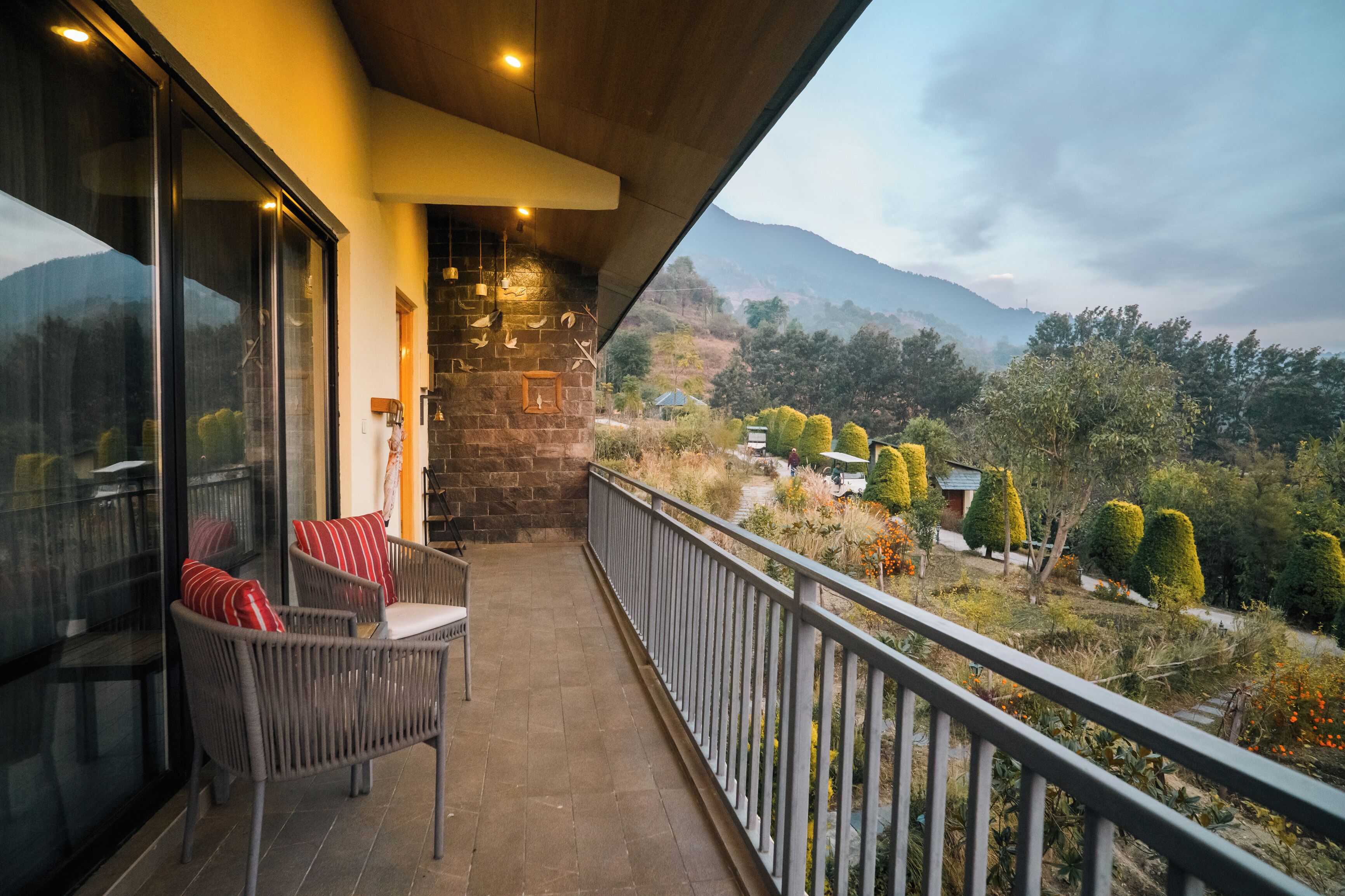 A balcony with wicker chairs, a stone wall, and a view of the countryside.