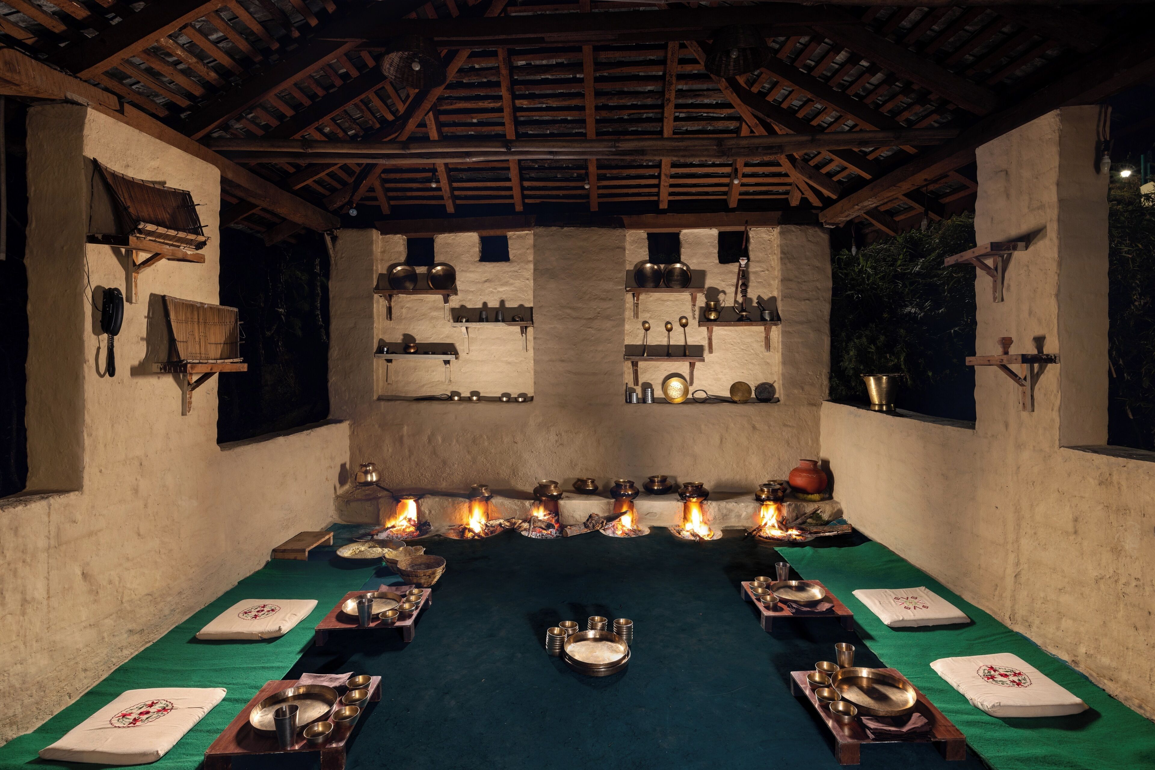 A traditional dining setup with a long table, multiple candles, and various dishes and utensils.