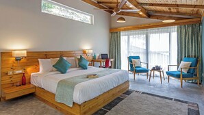 A bedroom with a wooden ceiling, a bed with pillows, a desk with a laptop, and two chairs. - Rakkh Resort (Palampur)