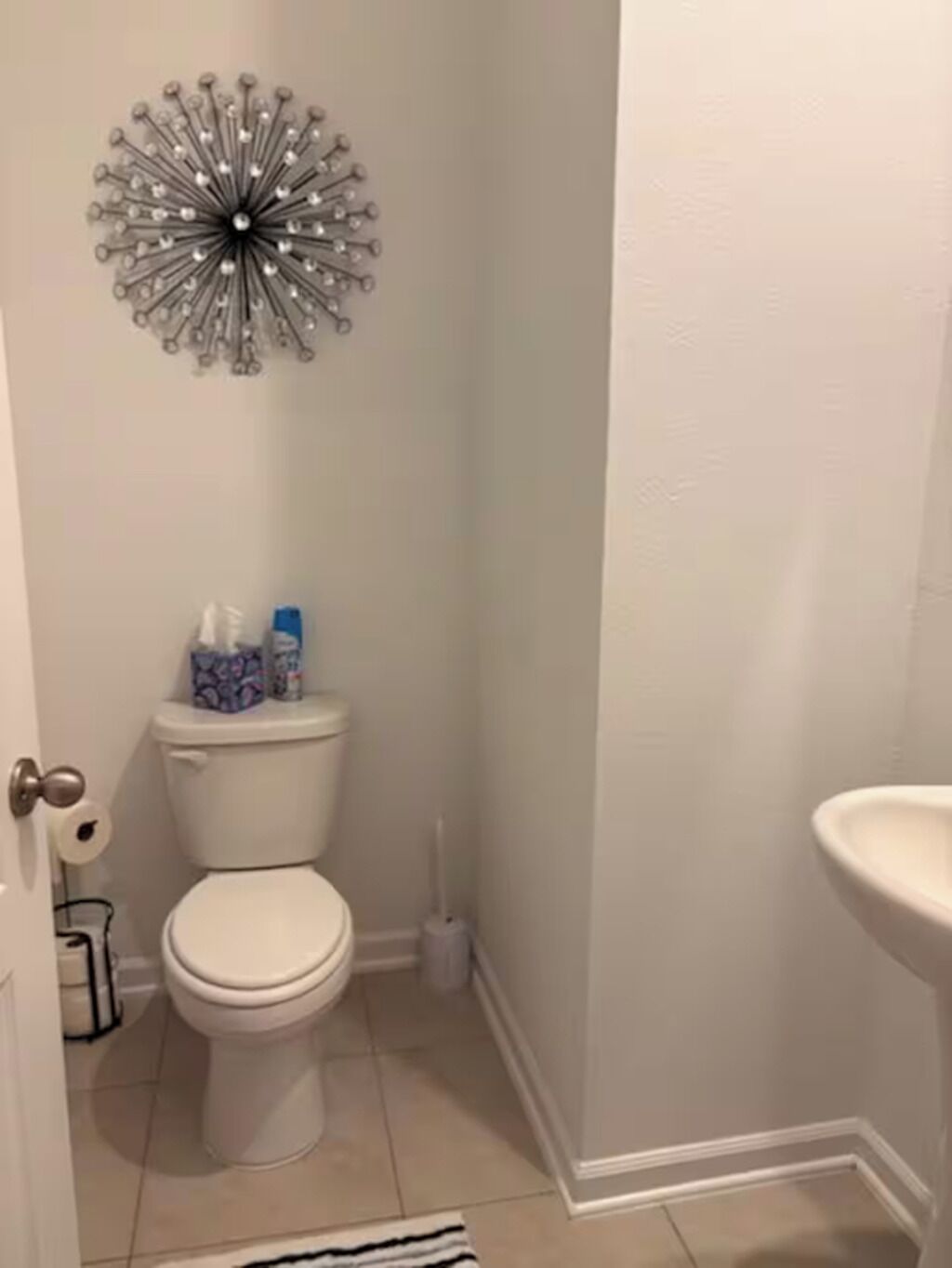 Un baño con inodoro, lavabo y un adorno de pared.