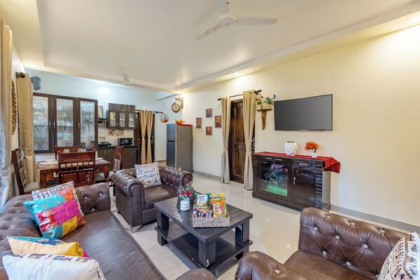 A living room with a sofa, coffee table, and a television mounted on the wall. - Alaya Stays Cozy Nest 2 BHK Cottage (Bhimtal)