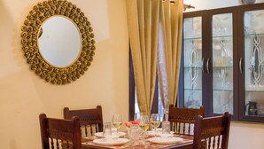 A dining table set for four with chairs, a mirror, and a cabinet with glass doors. - Alaya Stays Cozy Nest 2 BHK Cottage  (Bhimtal)